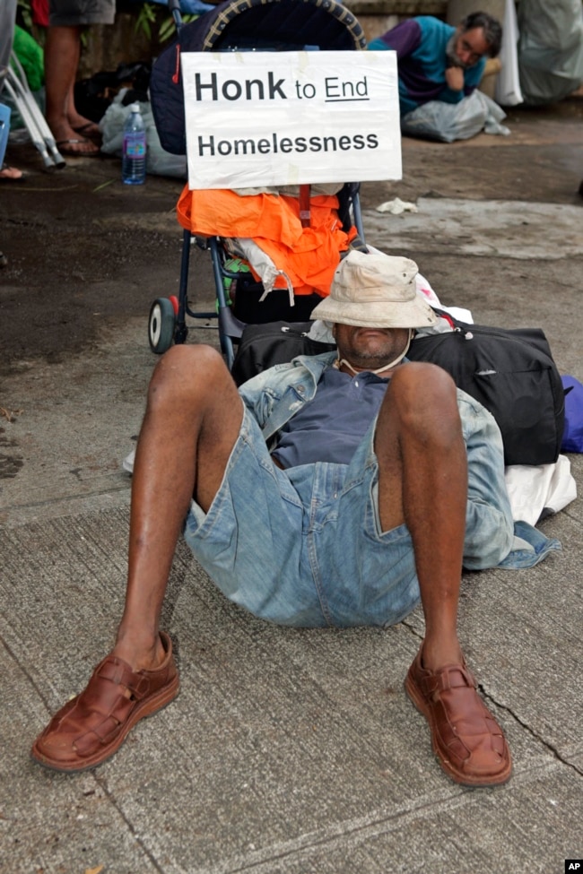 A man sleeps on the sidewalk in front of Honolulu Hale, Tuesday, March 28, 2006, in Honolulu after the City evicted groups of homeless people from Ala Moana beach park in order to begin renovations to park facilities.