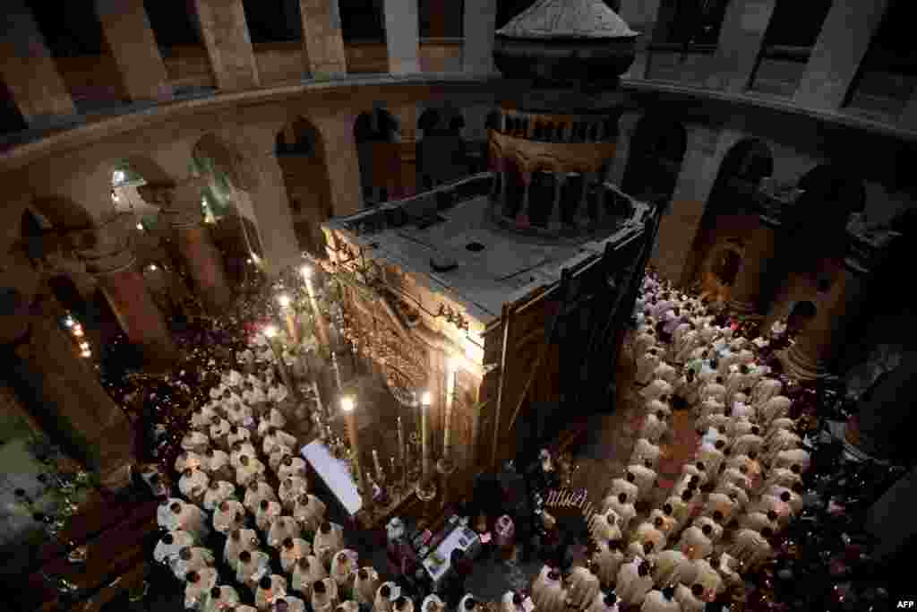 天主教教士手持蜡烛在耶路撒冷老城里的圣墓教堂做礼拜。