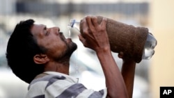 FILE - An Indian drinks water from a bottle on a hot summer day in Allahabad, India, May 31, 2015. 