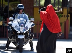 FILE - A Muslim woman leaves a protest as a San Diego police officer looks on after protesters marched through El Cajon, Calif., Oct. 1, 2016, in reaction to Alfred Olango's death.