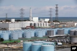 FILE - Nuclear reactors of No. 5, center left, and 6 look over tanks storing water that was treated but still radioactive, at the Fukushima Daiichi nuclear power plant in Okuma town, Fukushima prefecture, northeastern Japan, Feb. 27, 2021.