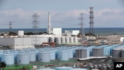 FILE - Nuclear reactors of No. 5, center left, and 6 look over tanks storing water that was treated but still radioactive, at the Fukushima Daiichi nuclear power plant in Okuma town, Fukushima prefecture, northeastern Japan, Feb. 27, 2021.