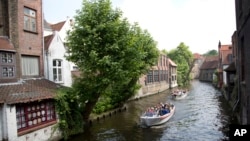 FILE - Tourists ride in a boat down a main canal in Bruges, Belgium, May 26, 2016. Tourism has dropped in Belgium since the deadly bombings in March.