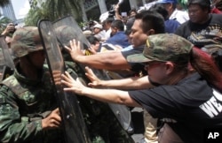 FILE - Protesters push Thai soldiers with shields during an anti-coup demonstration in Bangkok, Thailand, May 25, 2014.