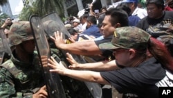 档案照片：2014年5月25日在泰国曼谷的一次反政变示威中，抗议者推压手持盾牌的军人。