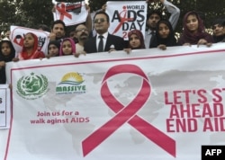 FILE - Pakistani social activists carry placards during a rally to raise awareness on World AIDS Day in Lahore, Dec. 1, 2016.