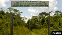 FILE - A sign marks the entrance of a former temple at a site deep in the Guyanese rainforest in Jonestown, Nov. 18, 2011.