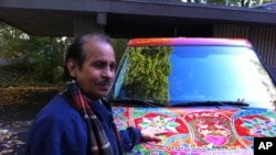 Pakistani truck and bus artist Ghulam Sarwar stands in front of a car he recently painted.