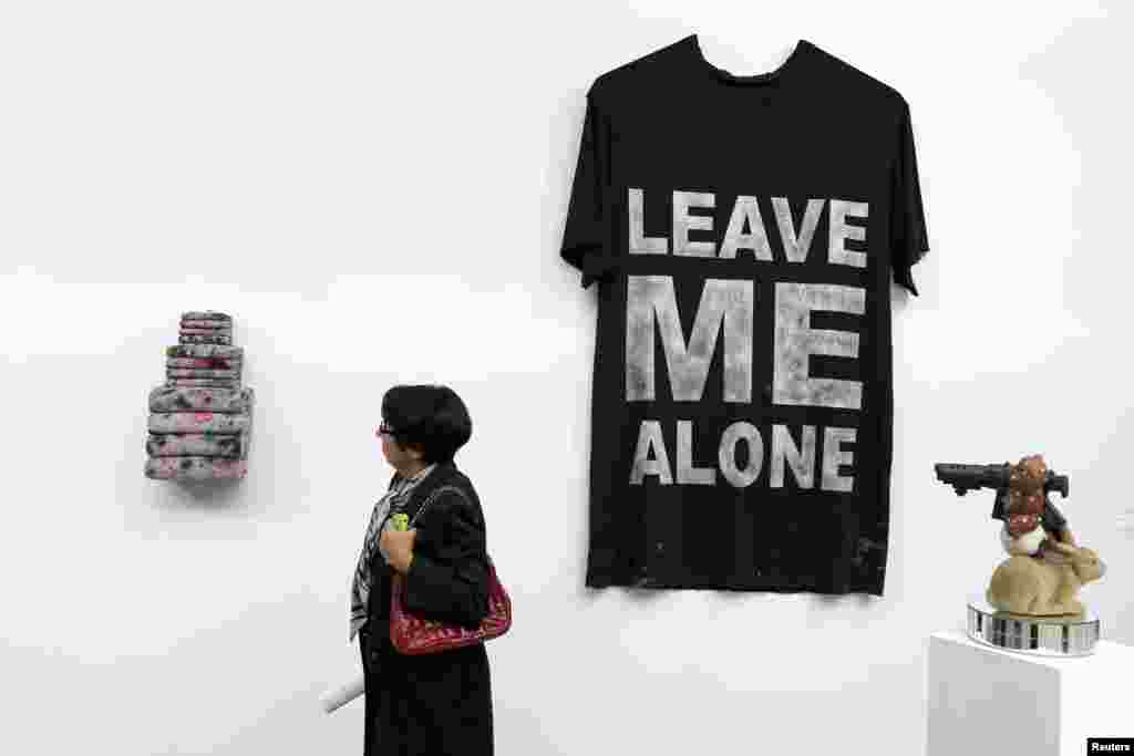 Seorang pengunjung berdiri disamping T-shirt dengan&nbsp;tulisan&nbsp;&quot;Leave Me Alone&quot; karya seniman Amanda Ross-Ho pada pameran seni kontemporer di Grand Palais,&nbsp;Paris, Perancis. 
