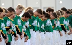 Jugadores de béisbol de la secundaria Santa Fe, observan un momento de silencio en honor de las víctimas de un tiroteo en su escuela. Mayo 19, 2018.