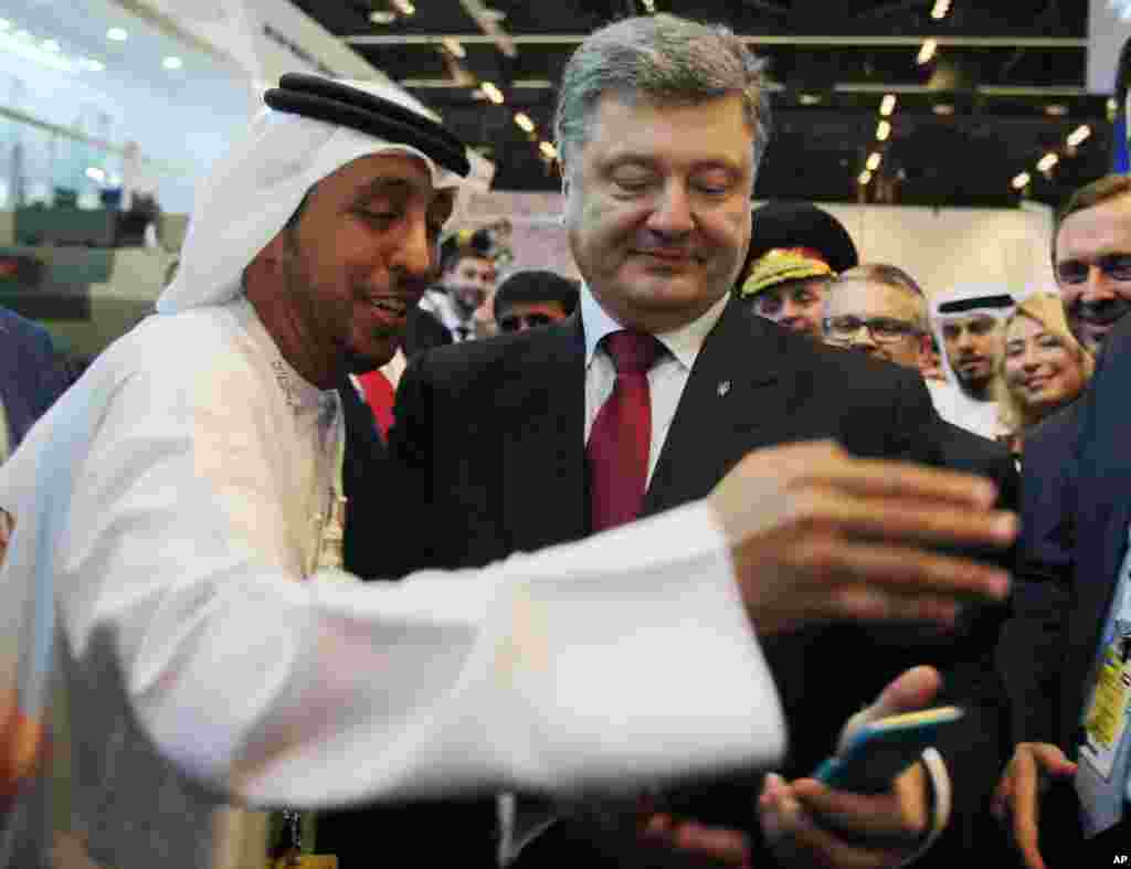 Presiden Ukraina Petro Poroshenko melihat selfie atau swafotonya dengan seorang representatif media Emirat di Pameran dan Konferensi Pertahanan Internasional (IDEX) di Abu Dhabi, Uni Emirat Arab (24/2). (AP/Kamran Jebreili)