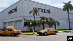Taxi's pass by a Macy's department store, Jan. 5, 2017, in Doral, Florida. The struggling department store said it will eliminate 10,000 jobs as it continues to close stores.