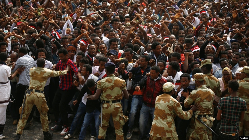 FILE - Demonstrators chant slogans while flashing the Oromo protest gesture during Irreecha, the thanksgiving festival of the Oromo people, in Bishoftu town, Oromia region, Ethiopia, Oct. 2, 2016.