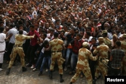 FILE - Demonstrators chant slogans while flashing the Oromo protest gesture during Irreecha, the thanksgiving festival of the Oromo people, in Bishoftu town, Oromia region, Ethiopia, Oct. 2, 2016.