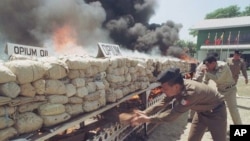 Burmese narcotic control officials put more wood to burn some six tons of seized opium, heroin and other drugs before diplomats, journalists and international business leaders in Rangoon, Burma. (File Photo)