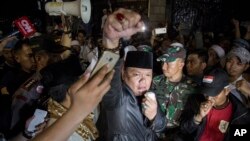 A protester raises his fist during an anti-communism rally outside the office of Legal Aid Institute early Sept. 18, 2017. A mob opposed to public discussion of Indonesia's 1965 massacre of communists tried to force its way into the building where they believed communists were meeting, injuring five policemen.