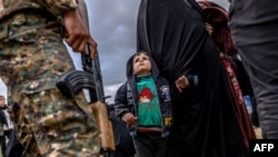 A young child looks at a member of the Kurdish-led Syrian Democratic Forces (SDF) after leaving the Islamic State (IS) group's last holdout of Baghuz, in Syria's northern Deir Ezzor province, Feb. 27, 2019.