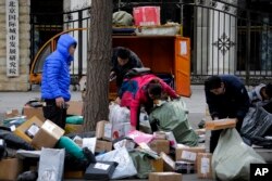 Delivery workers sort boxes of goods for their customers outside the capital city development academy in Beijing, China, Oct. 30, 2018. Surveys showed manufacturing in China weakened in December.