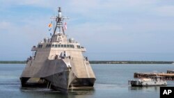 A Naval Station vessel, right, prepares to assist the future USS Omaha (LCS 12), a 218-foot-long littoral combat ship, pier side during a brief fuel stop in Guantanamo Bay, Cuba, Jan. 3, 2018. The Omaha was conducting a change of homeport to San Diego, Calif.