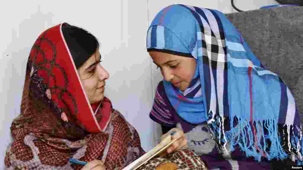 Malala Yousafzai, à gauche échange avec à une réfugiée syrienne âgée de 16 ans, Mazoon Rakan, de l&rsquo;expérience de Mazoon comme réfugiée dans ce camp de Zaatri, dans la ville de Mafrag, en Jordanie près de la frontière avec la Syrie, le 18 février 2014. REUTERS/Muhammad Hamed 