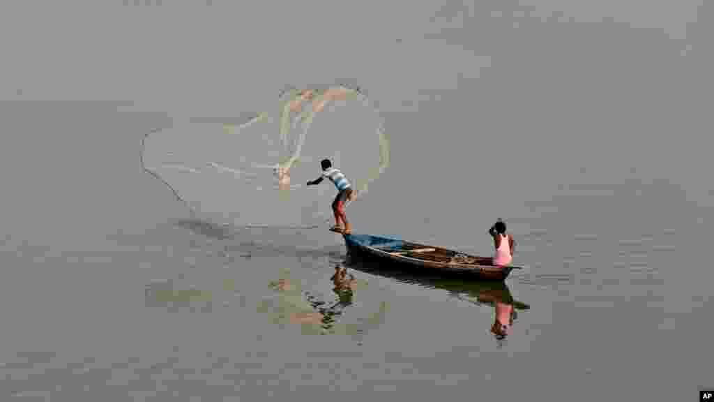 Un pêcheur indien jette son filet dans la rivière de Gomti à Lucknow en Inde,7 août 2015