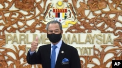 FILE - In this photo released by Malaysia's Information Ministry, Prime Minister Muhyiddin Yassin poses for a picture at the parliament, in Kuala Lumpurf, Malaysia Thursday, Nov. 26, 2020. 