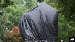 Residents and visitors look over the covered statue of Confederate General Robert E. Lee in Emancipation park in Charlottesville, Va., Aug. 23, 2017. The move to cover the statues is intended to symbolize the city's mourning for Heather Heyer, killed whil