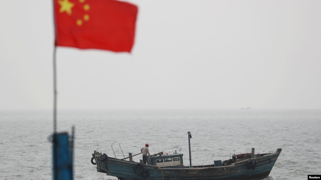 石油泄漏事故后，山东青岛港飘扬的国旗下有一艘渔船。（2021年4月28日）(photo:VOA)
