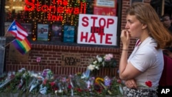 A woman cries and holds flowers in front of a makeshift memorial to remember the victims of a mass shooting in Orlando, Fla., in New York, Sunday, June 12, 2016