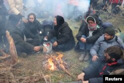 Migrants gather around a fire on the Belarusian-Polish border near the Bruzgi-Kuznica Bialostocka border crossing in the Grodno Region, Belarus, Nov. 15, 2021.