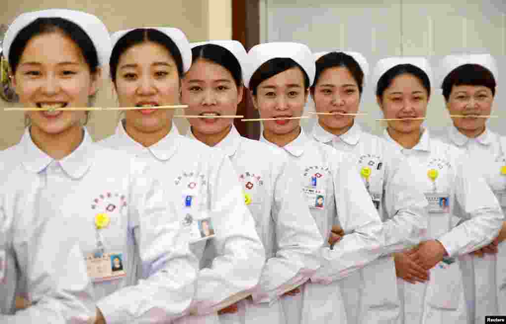 중국 허베이성 한단의 간호사들이 젓가락을 문 채 미소짓는 연습을 하고있다. &nbsp;