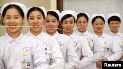 Des infirmières s'exercent à sourire avec des baguettes dans la bouche en Chine, le 8 mai 2017.