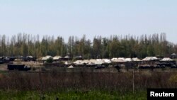 FILE - Russian military vehicles and army tents are seen in a field outside the village of Severny in Belgorod region near the Russian-Ukrainian border, April 25, 2014.