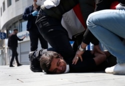 FILE - In this May 1, 2020, file photo, Turkish police officers arrest a demonstrator wearing a face mask for protection against the coronavirus, during May Day protests near Taksim Square, in Istanbul.