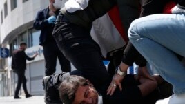FILE - In this May 1, 2020, file photo, Turkish police officers arrest a demonstrator wearing a face mask for protection against the coronavirus, during May Day protests near Taksim Square, in Istanbul.