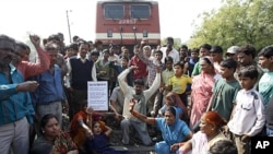 Survivors of the Bhopal gas tragedy and other supporters shout slogans as they lie on a railway track to stop train movement during a protest on a railway track in Bhopal, India, Saturday, Dec. 3, 2011.