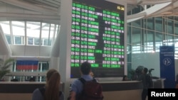 International passengers are seen near the flight information board at Ngurah Rai Bali International Airport, Kuta, Bali, Indonesia, Dec. 2, 2017.