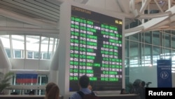 Turis asing terlihat di dekat papan informasi penerbangan di Bandara Internasional Ngurah Rai Bali, Kuta, Bali. (Foto: REUTERS/Kanupriya Kapoor)