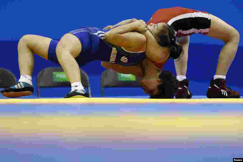 Uzbekistan&#39;s Shakhodat Djullibaeva (L) and Egypt&#39;s Habiba Ismail grapple during their women&#39;s freestyle 52 kg qualification match at the 2014 Nanjing Youth Olympic Games in Nanjing, Jiangsu province, China.