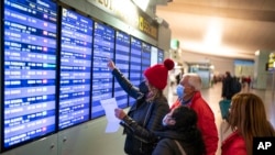 DOSSIER - Des passagers regardent un écran d'informations de vol à l'intérieur d'un terminal de l'aéroport de Barcelone, le 1er décembre 2021.