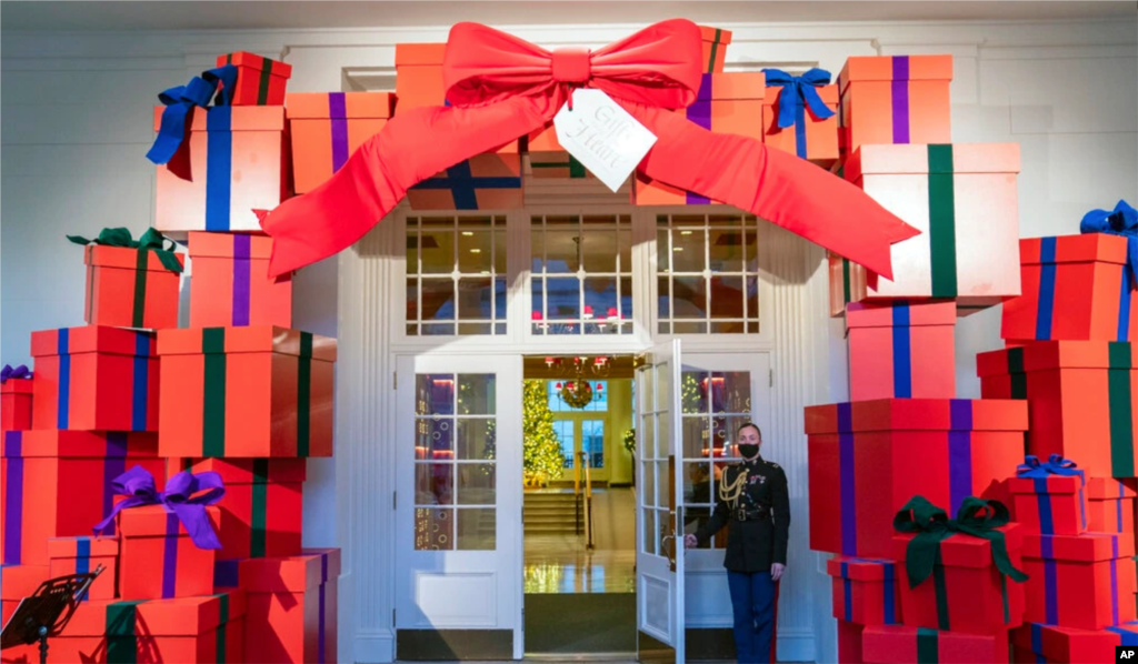 Un asistente social militar de la Casa Blanca de la Marina sostiene la puerta de la entrada del Ala Este de la Casa Blanca durante una vista previa para la prensa de las decoraciones navideñas de la Casa Blanca, el 29 de noviembre de 2021.