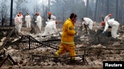 A volunteer search and rescue crew from Calaveras County comb through a home destroyed by the Camp Fire in Paradise, California, U.S., Nov. 13, 2018. 