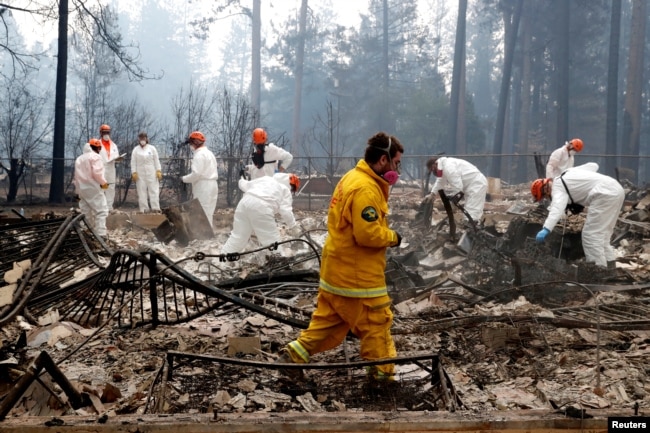 A volunteer search and rescue crew from Calaveras County comb through a home destroyed by the Camp Fire in Paradise, California, Nov. 13, 2018.