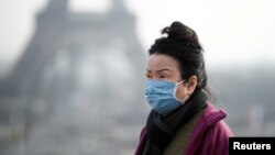巴黎市埃菲尔铁塔前一名女子戴上口罩（路透社2020年1月25日）