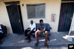 Woodchy Darius, right, sits outside the small cinderblock apartment he lives in, in the aftermath of Hurricane Irma, in Immokalee, Florida, Sept. 12, 2017.