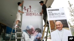 Công nhân dựng poster hình ảnh Đức Giáo Hoàng Phanxicô tại Trung tâm Văn hóa Sejong ở Seoul, Hàn Quốc, ngày 8/5/2014.