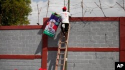 En esta foto de archivo del 11 de octubre de 2015, los activistas cuelgan un póster del candidato presidencial Eric Jean Baptiste en Carrefour, Haití. Jean-Baptiste fue herido el lunes 1 de octubre de 2018 en un ataque armado mientras conducía su vehículo en un vecindario al sur de Puerto Príncipe. (AP Photo / Dieu Nalio Chery).