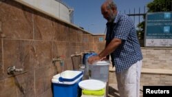Seorang pria mengisikan air ke dalam jerikendi Derna, Libya, 13 Juni 2018.

