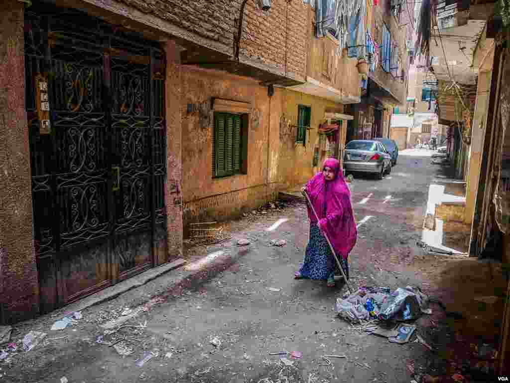 An Egyptian woman cleans in front of her house in Giza, Egypt on May 18, 2015 after what authorities said was a fight between the police and two suspected terrorists. The suspects were killed but analysts say there was no evidence of a battle on the streets. (H. Elrasam/VOA)