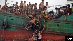 Rohingya migrants pass food supplies dropped by a Thai army helicopter to others aboard a boat drifting in Thai waters off the southern island of Koh Lipe in the Andaman sea on May 14, 2015. 